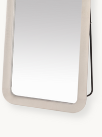 Close-up of lower half of white suede velvet framed standing mirror showing rounded corner detail and black metal back sup…