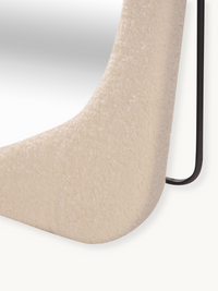 Close-up of cream white bouclé teddy fabric upholstery on the lower curve of the Felis mirror frame, black metal leg visible