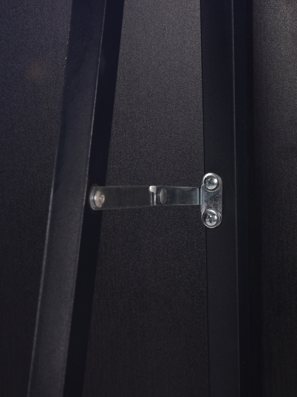 Close-up of silver metal hinge bracket screwed across two black wood frame sections on the back of the mirror
