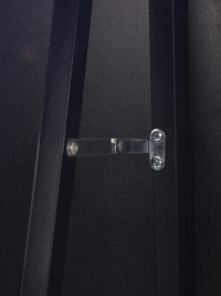 Close-up of silver metal hinge bracket screwed across two black wood frame sections on the back of the mirror