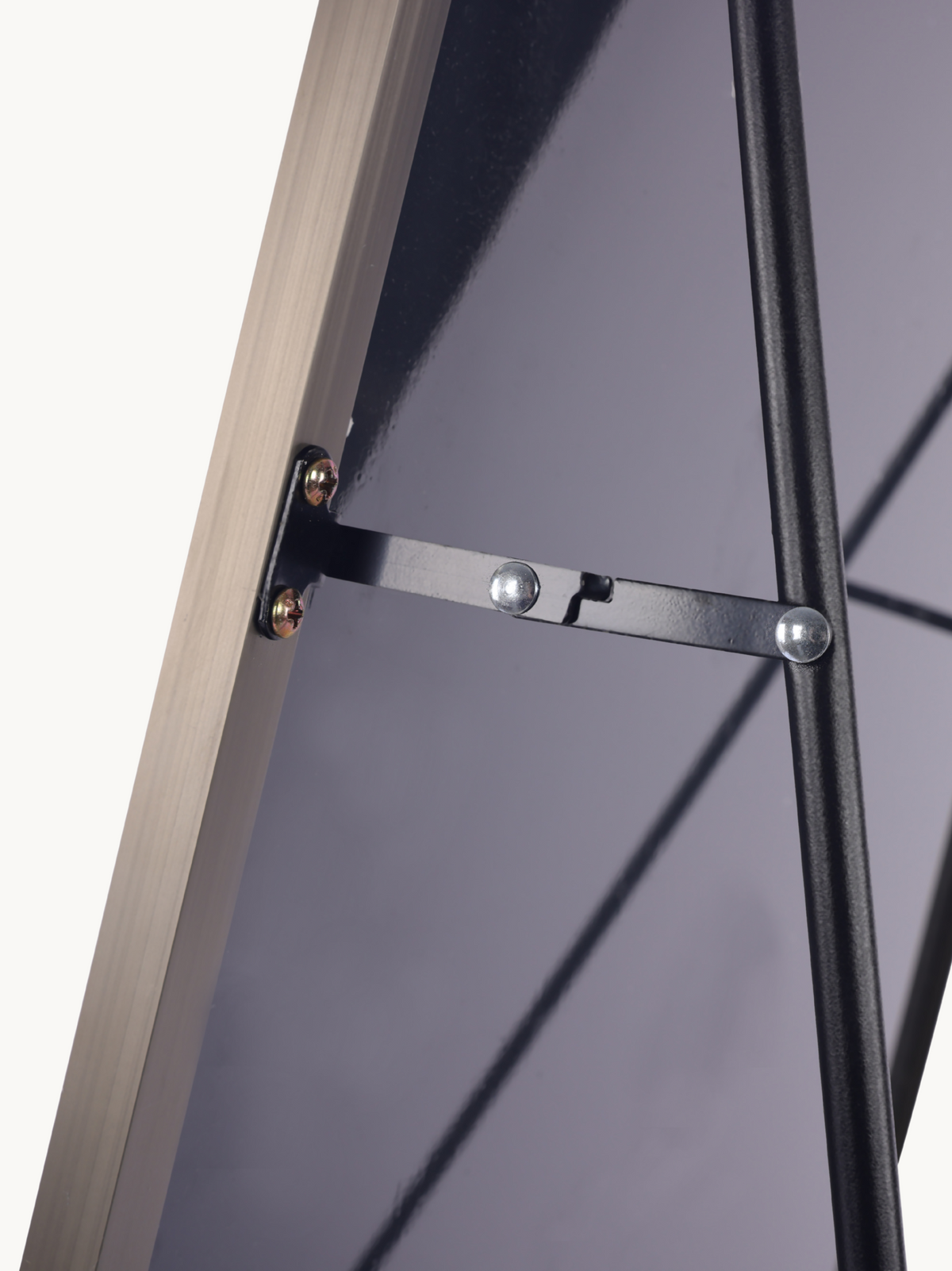 Close-up of black metal hinge bracket and screws connecting taupe aluminium frame to back support strut of standing mirror