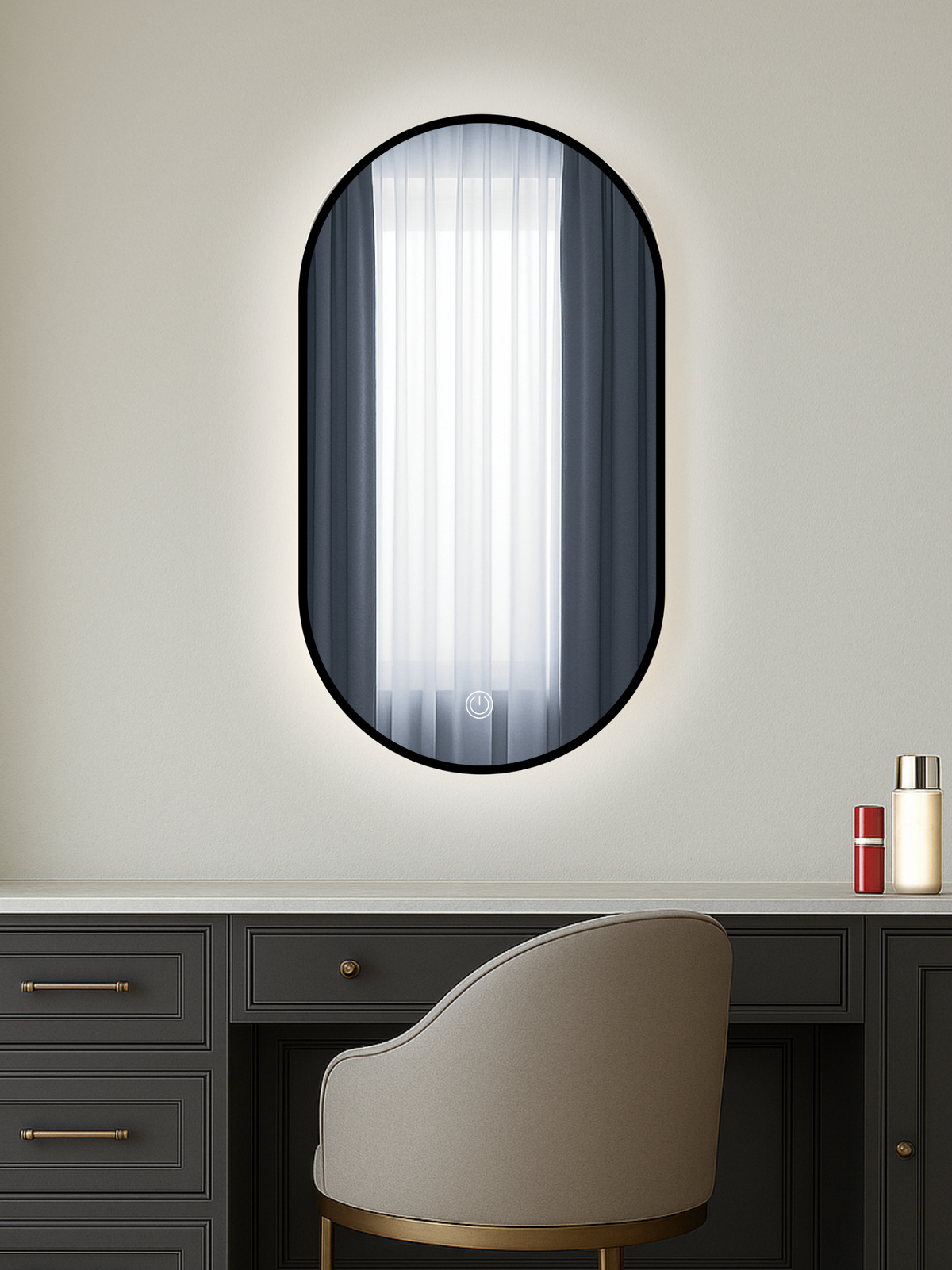 Oval black-framed LED mirror above a dark dressing table with beige chair, warm backlight aglow, touch control icon visible
