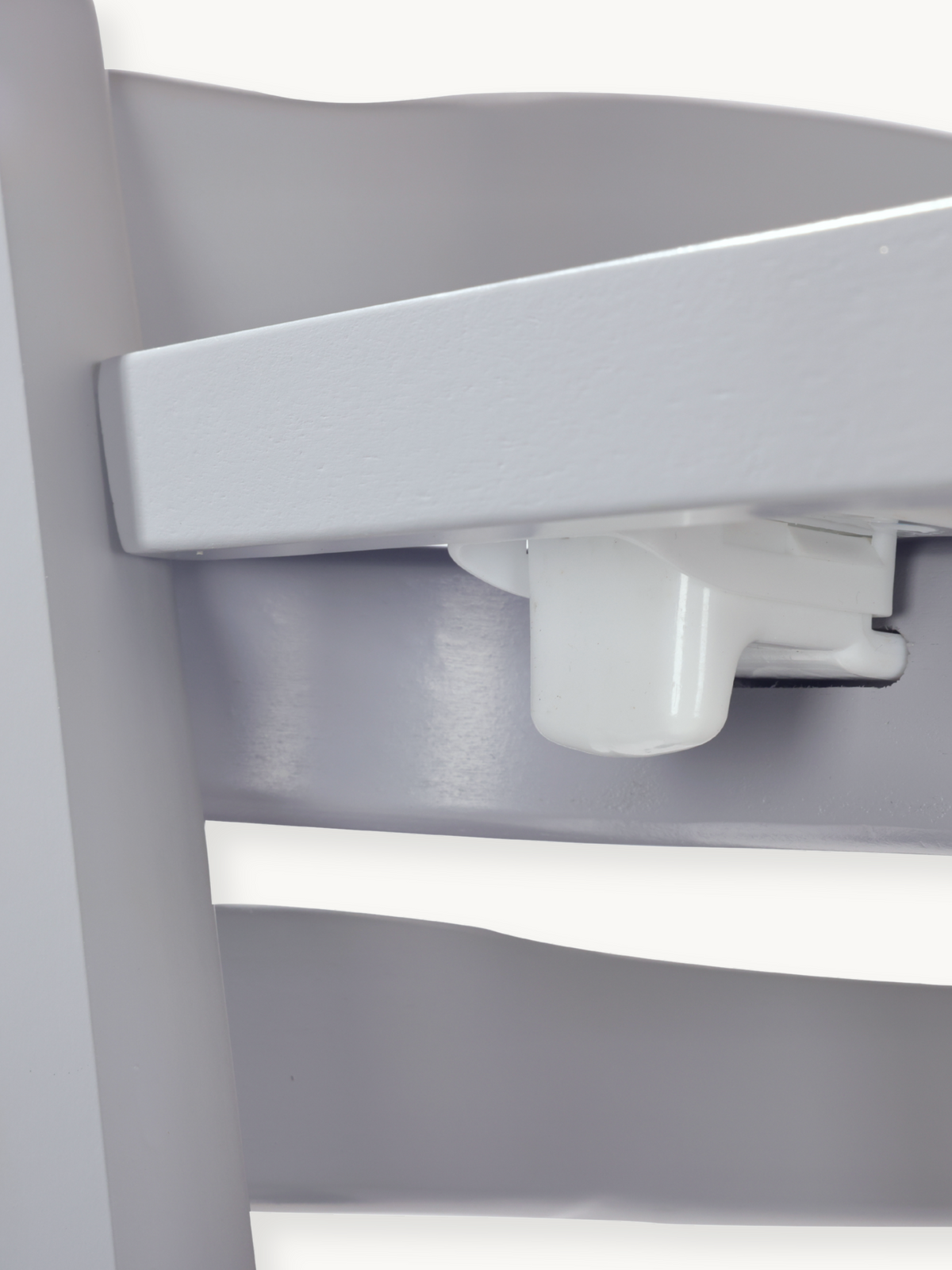 Close-up of white plastic tray locking mechanism underneath the grey wooden highchair tray, showing release button detail