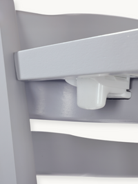 Close-up of white plastic tray locking mechanism underneath the grey wooden highchair tray, showing release button detail