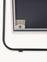 Close-up of mirror bottom corner showing silver wall-mounting bracket and black cable management clip on aluminium frame back