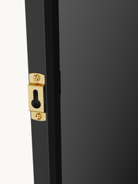 Close-up of gold-tone keyhole wall-mount bracket screwed into black aluminium mirror frame edge