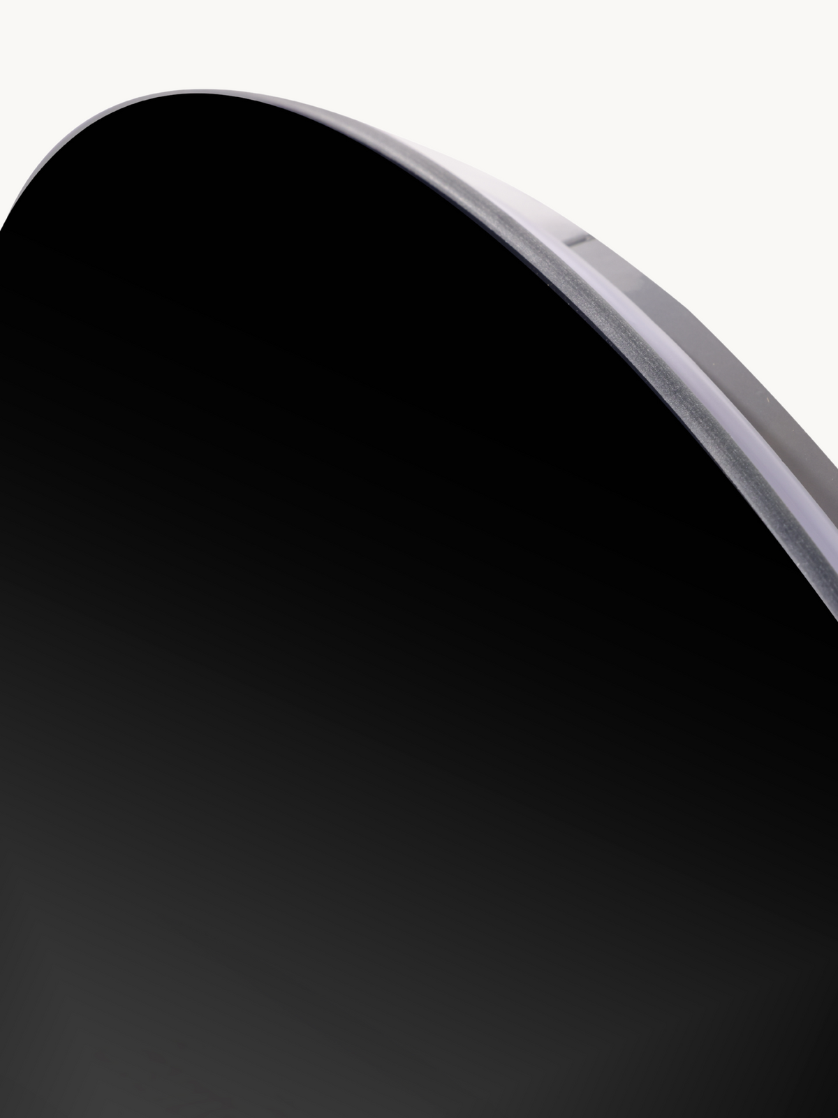 Close-up of the upper-right curved edge of a round frameless mirror, showing 5 mm black-tinted glass thickness and clear rim