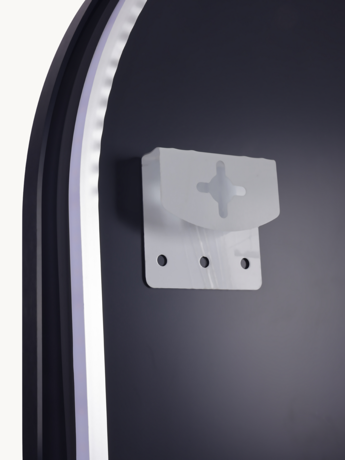 Close-up of translucent plastic wall-mounting bracket with cross-slot and three screw holes, against dark mirror back surf…