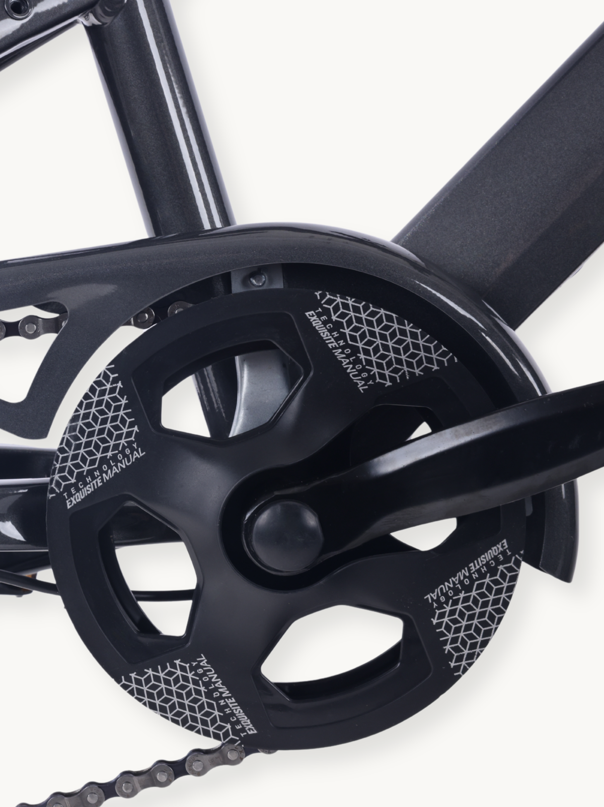 Close-up of black chainring and crankset on grey steel frame, chain visible at bottom, geometric pattern graphics on ring