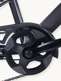 Close-up of black chainring and crankset on grey steel frame, chain visible at bottom, geometric pattern graphics on ring