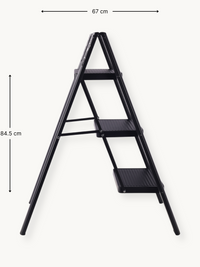 Black 3-step folding ladder angled side view with dimension annotations: 67 cm wide and 84.5 cm tall, white background