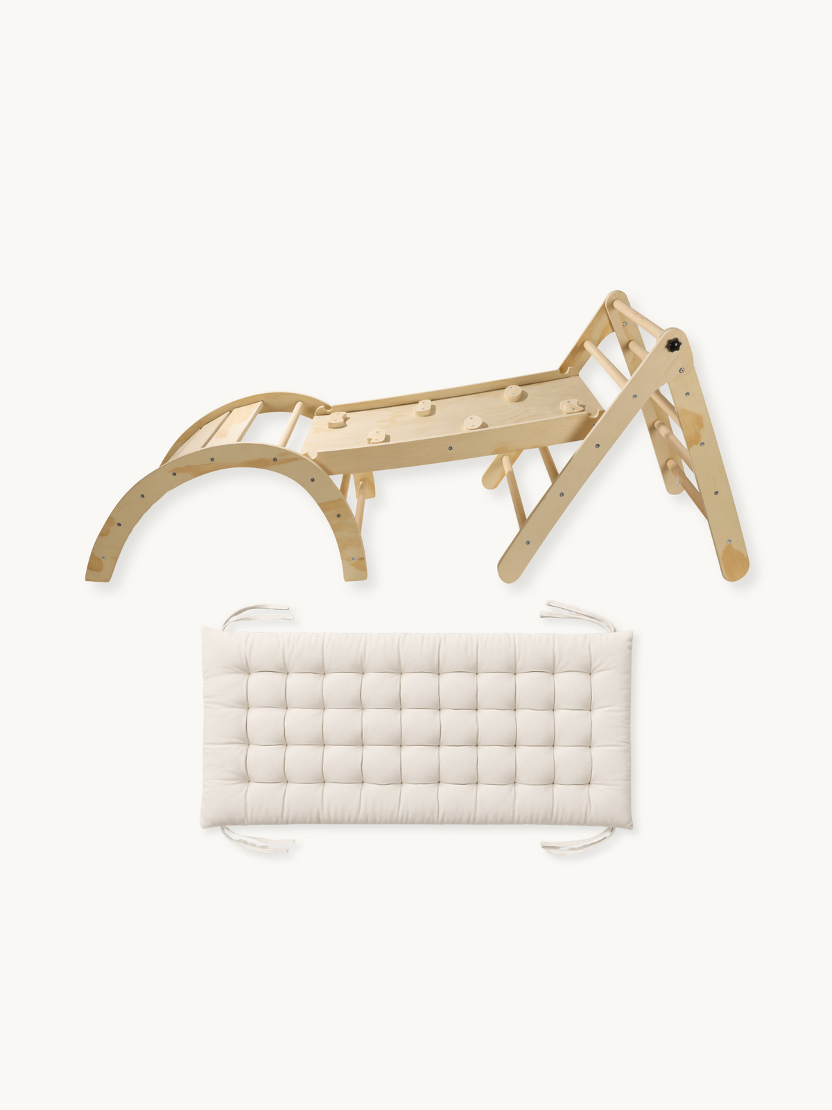 Natural wood Pikler-style climbing set with triangle, ramp, and arch beside a cream tufted rectangular cushion with ties