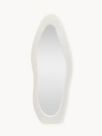 Tall asymmetric oval standing mirror with a chunky white teddy fabric frame, front view on plain background