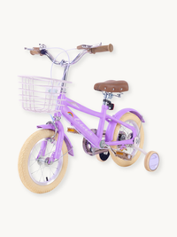 Purple Luna 12-inch girls' bike angled front view, showing wire basket, brown grips, cream tyres, and training wheels on w…