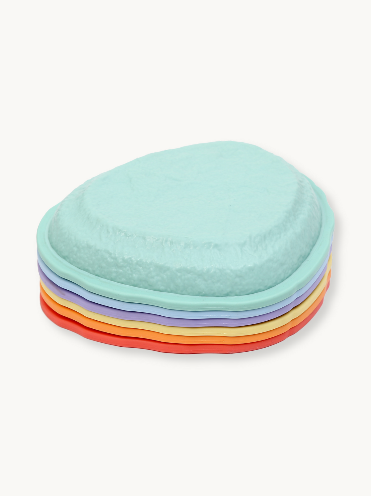 Six pastel balance stones stacked in a neat pile, showing mint, lavender, yellow, orange, and red layers, angled view on w…