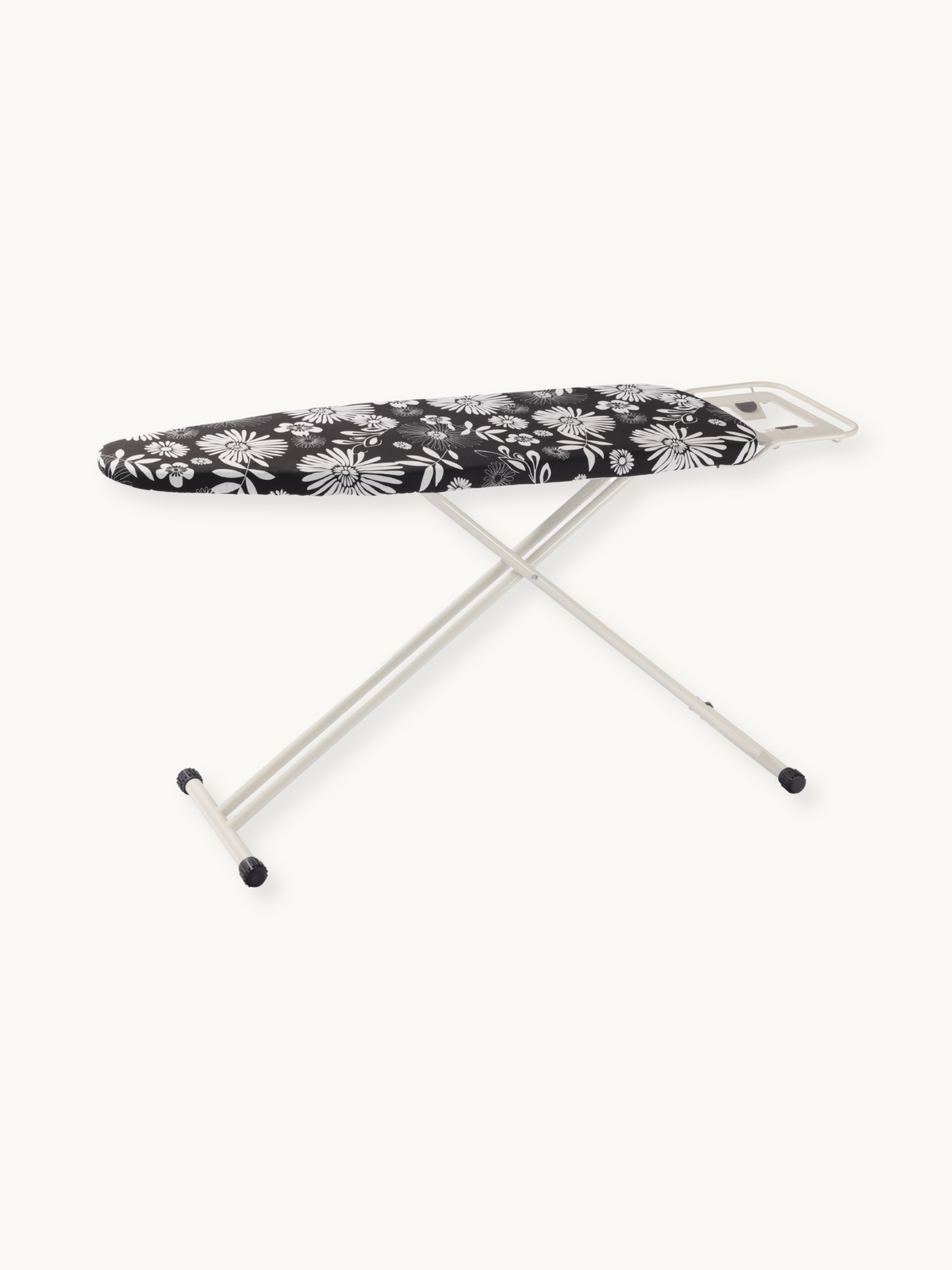 Ironing board with black and white daisy floral cotton cover, silver steel X-frame legs and iron rest, angled side view