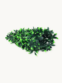 Coiled roll of artificial green leaf garland strips loosely bundled, showing dark and bright green plastic foliage, white…