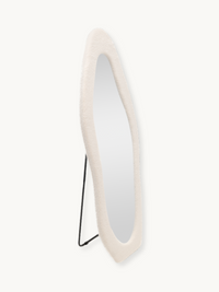 Angled side view of Seraphina floor mirror showing white teddy fabric frame depth and slim black metal easel stand