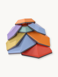 Eight multicolour hexagonal balance stones stacked in a dome formation, showing faceted tops in red, orange, blue, purple,…