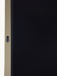 Close-up of gold aluminium frame edge showing a small circular keyhole-shaped wall-mount fitting on a black mirror panel