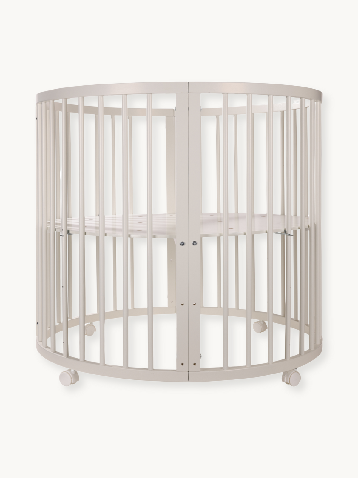 Round white wooden baby playpen with vertical slats, oval shape, adjustable mattress base, and lockable castors, front vie…