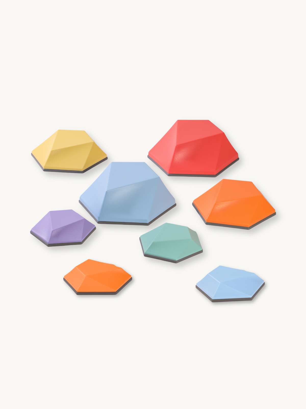 Eight multicolour hexagonal balance stones in three sizes, scattered on white background, with faceted tops and dark non-s…