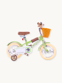 Green Luca 12-inch children's bike, side view, with cream rubber tyres, wicker front basket, brown leather saddle, and tra…
