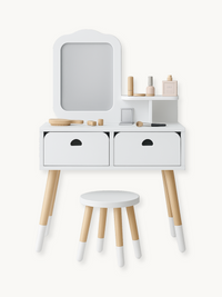 White children's wooden vanity table with mirror, two drawers, side shelf, matching round stool, and toy accessories on ne…