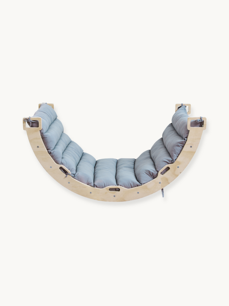 Curved wooden Montessori climbing arch with fitted grey tufted cushion, front view on white background