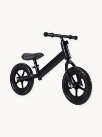 Matte black kids balance bike with five-spoke wheels, padded saddle, and T-bar handlebars, shown at a slight angle on whit…
