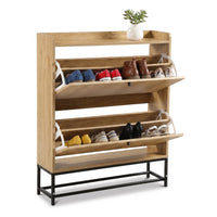 Oak-finish shoe cabinet with two open flip-down compartments displaying mixed shoes, small succulent on top shelf, black m…