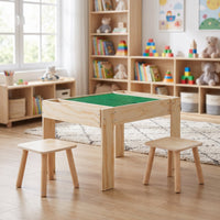 Natural wood kids' building table with green brick plate top and two stools styled in a bright playroom, front three-quart…