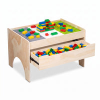 Natural wood play table angled view showing colourful bricks built on three baseplates and open front drawer filled with l…