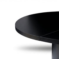 Close-up of black matte round tabletop edge and upper ribbed pedestal base, showing panel join seam detail, white background