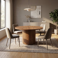 Walnut round dining table with herringbone top and ribbed pedestal base styled in a bright dining room with four upholster…