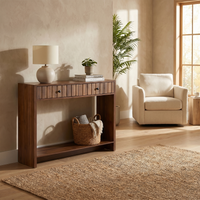 Walnut console table styled in warm living room with lamp, stacked books and plant on top, wicker basket on open lower shelf