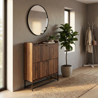 Walnut shoe cabinet with ribbed flip-down doors styled in a hallway with round mirror, fiddle-leaf fig, and jute runner