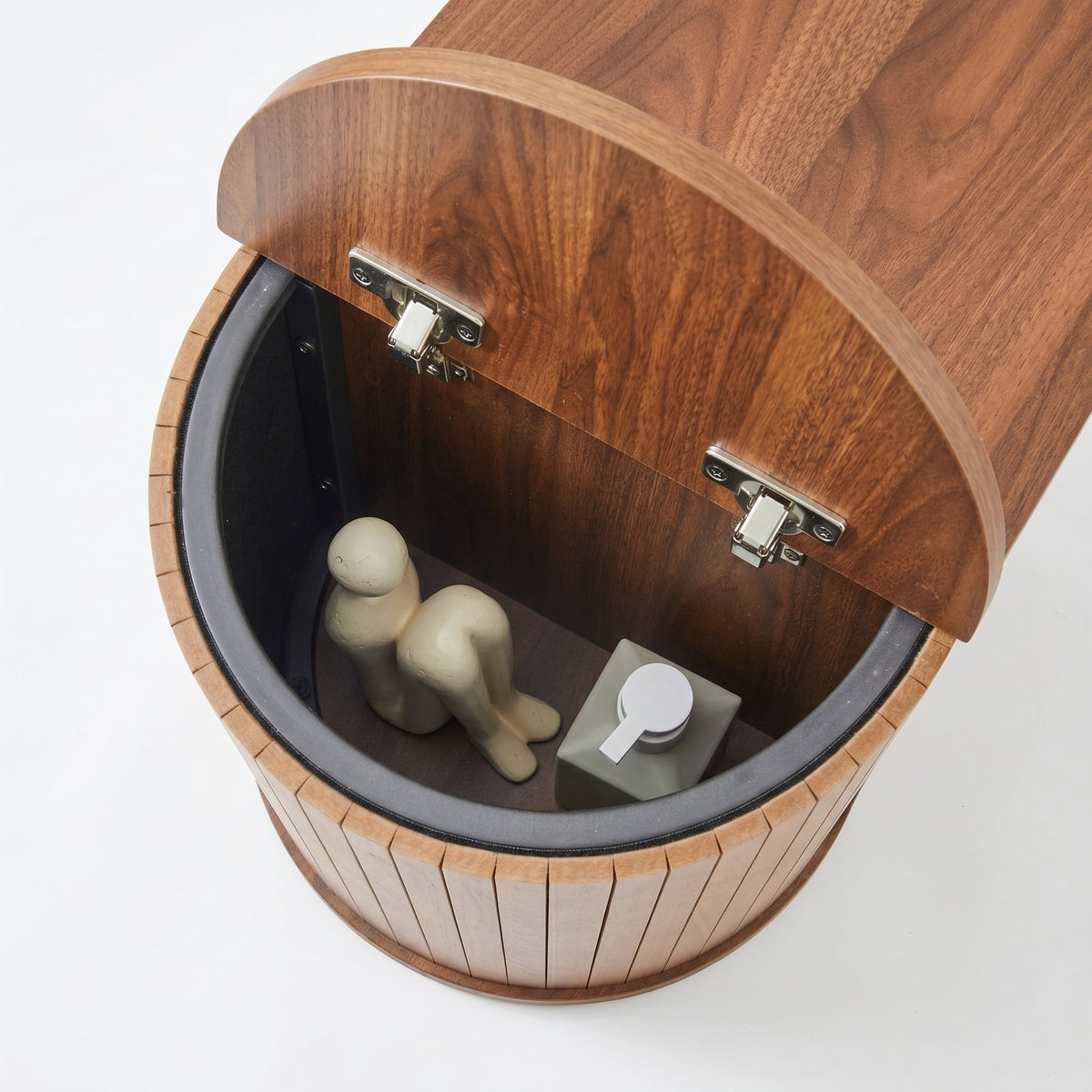Top-down view inside open flip-top compartment of walnut oval shoe bench, black inner lining, silver hinges visible, small…