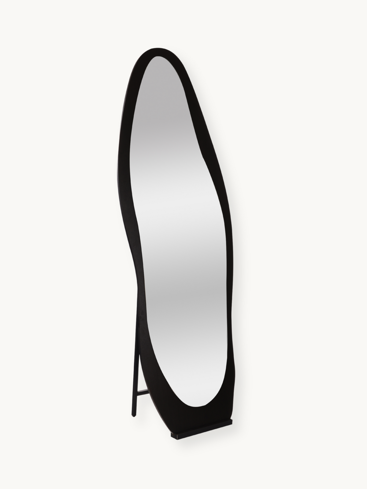 Black asymmetric oval floor mirror with wavy black wood frame, angled three-quarter view on plain background, easel stand…