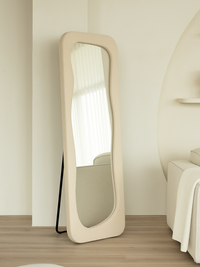 Felis standing mirror in teddy white, leaning against wall on metal support stand, wavy glass visible, bedroom lifestyle s…