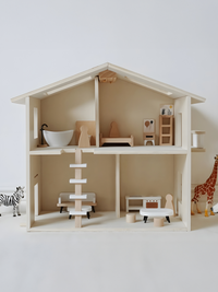 Front-facing natural wood dolls house with miniature bath, bed, kitchen, staircase, and zebra and giraffe figures placed e…