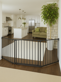Black metal freestanding safety gate configured in a curved enclosure on hardwood floor, lifestyle view in open-plan livin…