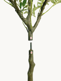 Two-section faux olive tree trunk separated at the connector joint, showing red arrow assembly guides on each section