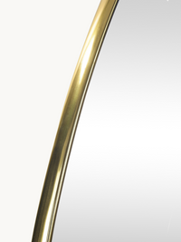 Close-up detail of brushed gold PVC frame on Luciano mirror, showing curved edge and metallic finish texture