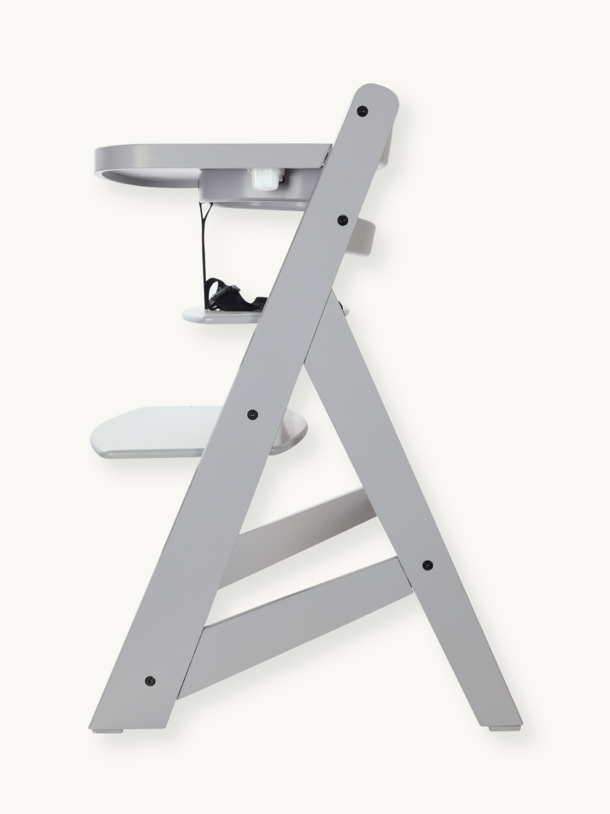 Grey wooden highchair side profile view showing A-frame legs, adjustable footrest, attached tray, and black safety harness…