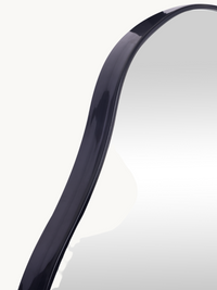 Close-up of upper curve of black gloss PVC frame on organic-shaped Matteo wall mirror, showing frame profile and mirror su…