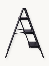 Black metal 3-step folding ladder open, side-angle view showing ribbed step treads, A-frame silhouette, and slim profile a…