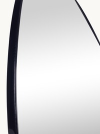 Close-up of Alaric mirror's curved black PVC frame edge, showing frame depth and glass surface detail against off-white ba…