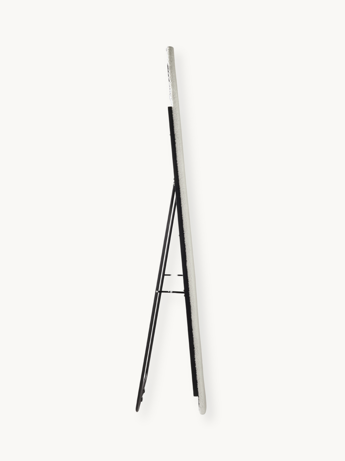Side profile of white teddy fabric oval floor mirror on black metal easel stand, showing slim edge depth against plain bac…