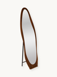 Angled side view of full-length asymmetric oval mirror in warm walnut-finish wood frame with black metal easel stand